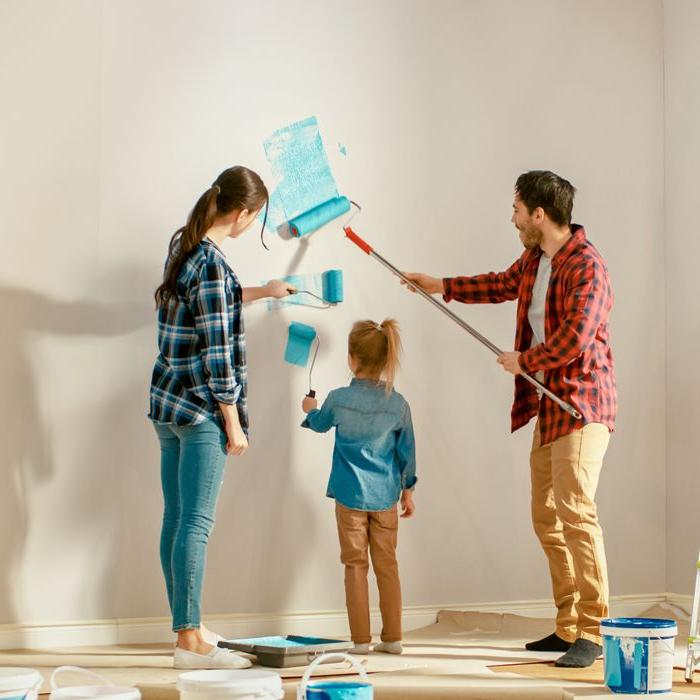 A mom, dad and daughter painting a wall turquoise.